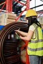 Asian female industrial worker in uniform and hardhat checking an inventory, working in factory Royalty Free Stock Photo