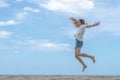 Female making jump on sandy beach with blue sky Royalty Free Stock Photo