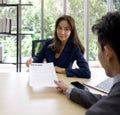 Asian female manager in blue suit received resume from young applicant. The atmosphere of job interview in the modern office