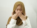 Asian female muslim woman covering her mouth due to bad breath, halitosis Royalty Free Stock Photo