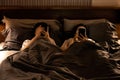 Asian female with nomophobia(No mobile phone phobia lying on bed using smartphone in bedroom at night or symptom of Reveng