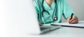 Asian female Nurse or Surgeon Doctor in green uniform working on laptop and writing something information of patient in paperwork Royalty Free Stock Photo