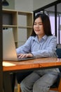 Asian female office worker working on her project, using laptop computer Royalty Free Stock Photo