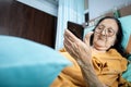 Southeast Asian female senior patient lying on hospital bed using smartphone Royalty Free Stock Photo