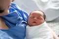 Asian female parent holding newborn baby with care on bed at hospital.