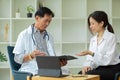 An Asian female patient consults with a middle-aged specialist doctor