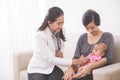 Asian female pediatrician examining a baby girl in the mother la Royalty Free Stock Photo