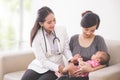 Asian female pediatrician examining a baby girl in the mother la Royalty Free Stock Photo