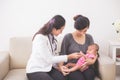 Asian female pediatrician examining a baby girl in the mother la Royalty Free Stock Photo