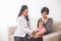 Asian female pediatrician examining a baby girl in the mother la Royalty Free Stock Photo