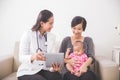 Asian female pediatrician showing something on tablet pc while a Royalty Free Stock Photo