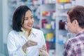 Asian female pharmacist or doctor explaining prescription medicine to patient female in a pharmacy Royalty Free Stock Photo