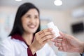 Asian Female pharmacist holding medicine white bottle giving advice to customer in chemist shop or pharmacy Thailand Royalty Free Stock Photo