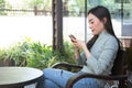 Asian female reading text message or social media on cell telephone during in modern cafe Royalty Free Stock Photo