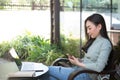 Asian female reading text message or social media on cell telephone during in modern cafe Royalty Free Stock Photo