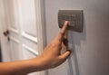 Asian female right hand is turning off on grey light switch Royalty Free Stock Photo