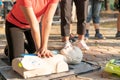 Asian female or runner woman training CPR demonstrating class in park by put hands and interlock finger over CPR doll give chest Royalty Free Stock Photo