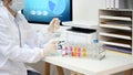 An Asian female scientist adjust a chemical liquid samples into a test tubes at her office desk Royalty Free Stock Photo