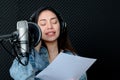 Asian female singer singing in a recording studio. Female singer singing and playing guitar