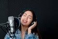 Asian female singer singing in a recording studio. Female singer singing and playing guitar Royalty Free Stock Photo