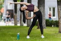 asian female sportswoman stretching near sport bottle of water on grass