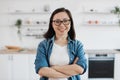 Asian female standing with crossed arms in home interior