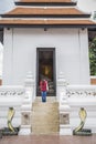 An asian female is standing and pray in front of a big buddha sculpture where is inside thai chapel