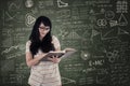 Asian female student reading book on chalkboard background Royalty Free Stock Photo