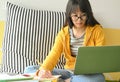 Asian female student wearing glasses is researching with a laptop and taking notes to make a report Royalty Free Stock Photo