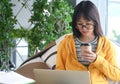 Asian female student wearing glasses is researching with a laptop to report, the other hand holding a coffee cup Royalty Free Stock Photo