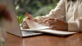 An Asian female student writing something in her book, taking notes while studying online Royalty Free Stock Photo