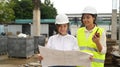 Asian female supervisor and architect checking plan inspect commercial building construction site Royalty Free Stock Photo