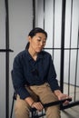 Asian female taskmaster sits in the background of cells with prisoners in a women's prison Royalty Free Stock Photo