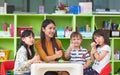 Asian female teacher and mixed race kids thumbs up in classroom,Kindergarten pre school concept. Royalty Free Stock Photo