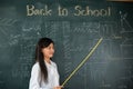 Asian female teacher smiling with wooden stick pointing to blackboard Royalty Free Stock Photo