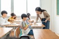 Asian Female Teacher talking Pupils studying at desks Royalty Free Stock Photo