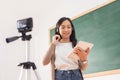 Asian Female teacher using digital tablet giving online lesson on digital camera Royalty Free Stock Photo