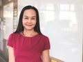 Asian female teacher wearing red dress, standing at white board in front of  classroom,  smiling and looking at camera. education Royalty Free Stock Photo