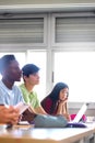 Asian female teen college student in class listening to lecture with multiracial classmates. Vertical. Copy space. Royalty Free Stock Photo