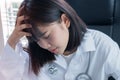 Asian Female teenage doctor physician looking  serious upset and holding hand over head headache on lab coat wearing stethoscope Royalty Free Stock Photo