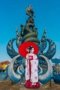 Asian female tourist in Chinese national costume stands admiring a blue statue in a temple in Chiang Rai Province, Thailand Royalty Free Stock Photo