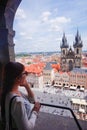 Asian female tourist looking down old town square from observatory of astronomical clock tower in Prague Royalty Free Stock Photo