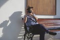 Asian female tourist photographing with digital camera while sitting on bench with white cement wall in vintage tone style Royalty Free Stock Photo