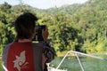 Asian female tourist taking photo with mobile phone while wearing life jacket on the boat