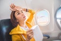 Asian female traveler suffers from an acute attack of nausea during turbulence on a plane. The woman was seasick and airsock Royalty Free Stock Photo