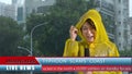 Asian female TV weather reporter reporting bad storm