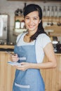 Asian female waiter in apron writing order Royalty Free Stock Photo