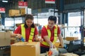 Asian female worker packing cardboard box with tape gun dispenser in warehouse. Thai employee packing goods in large industrial Royalty Free Stock Photo