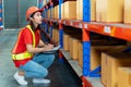 Asian female worker writing clipboard document. woman engineers wear safety hard helmet and vest checking storage box parcel in Royalty Free Stock Photo