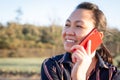An Asian Filipino woman happily talking on the phone during sunset. Close-up shot portrait